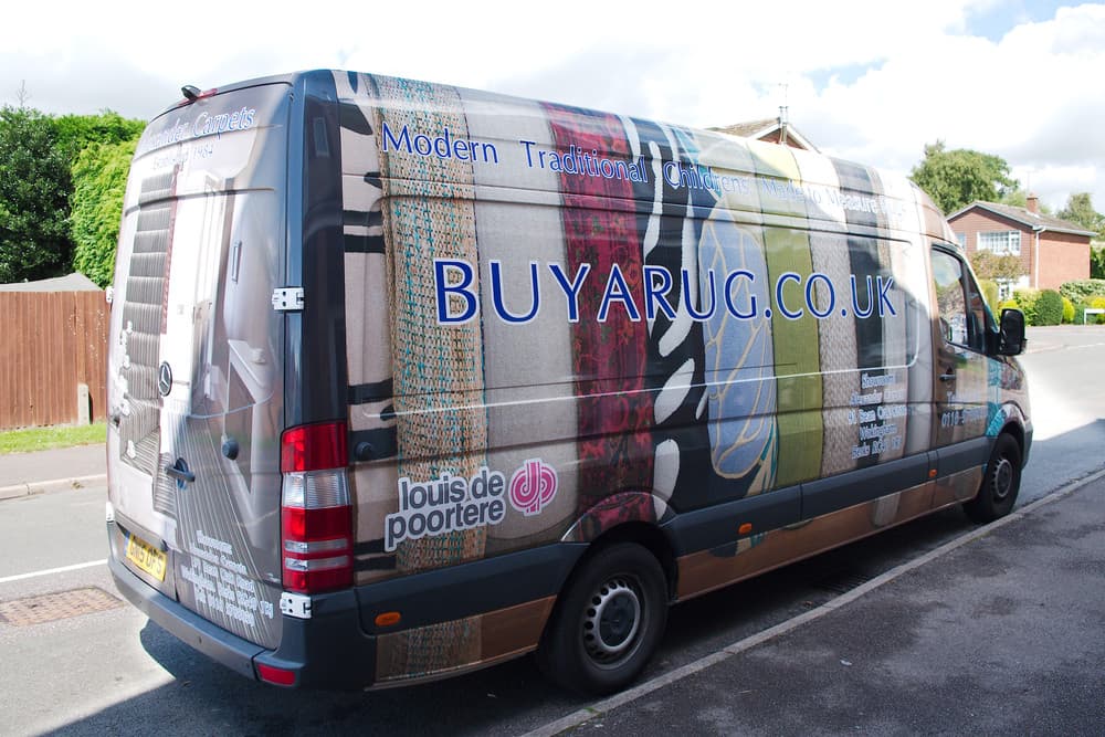 Black leather journal with silver steel disc binding resting on wooden shelf with machined steel pen.